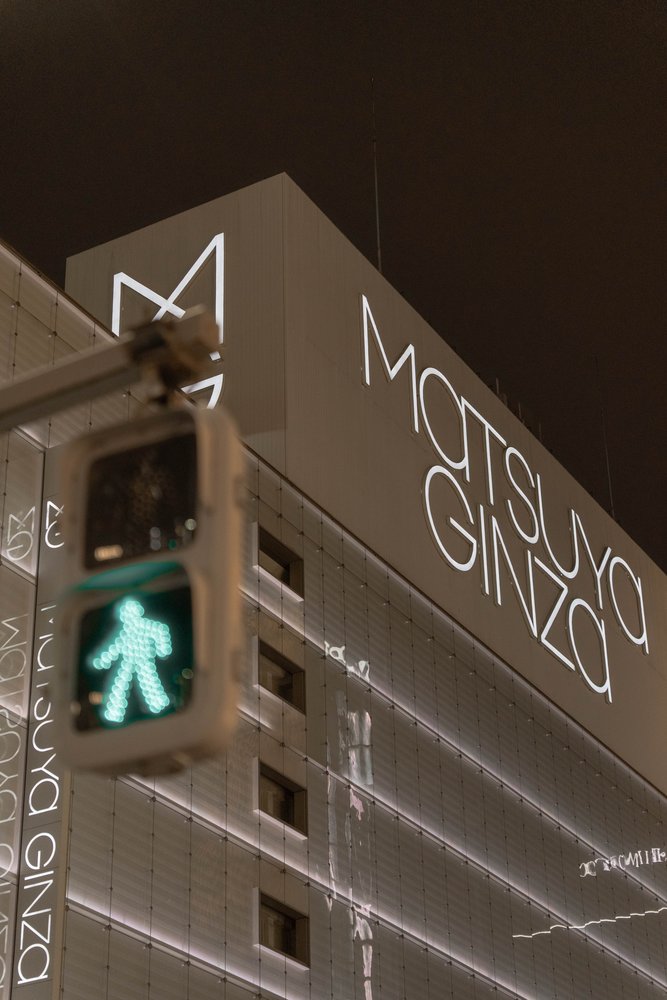 Matsuya Ginza department store building at night with a pedestrian crossing signal in the foreground — Zen Den Studios